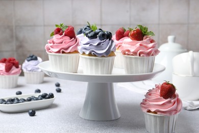 Photo of Tasty cupcakes with different berries on light grey table