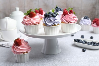 Photo of Tasty cupcakes with different berries on light grey table