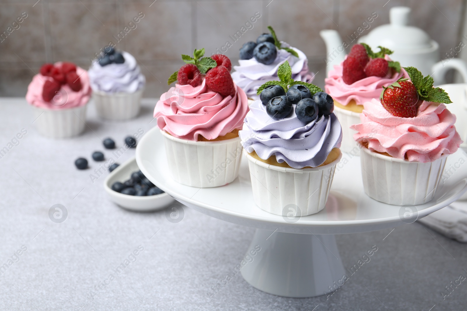 Photo of Tasty cupcakes with different berries on light grey table, closeup. Space for text