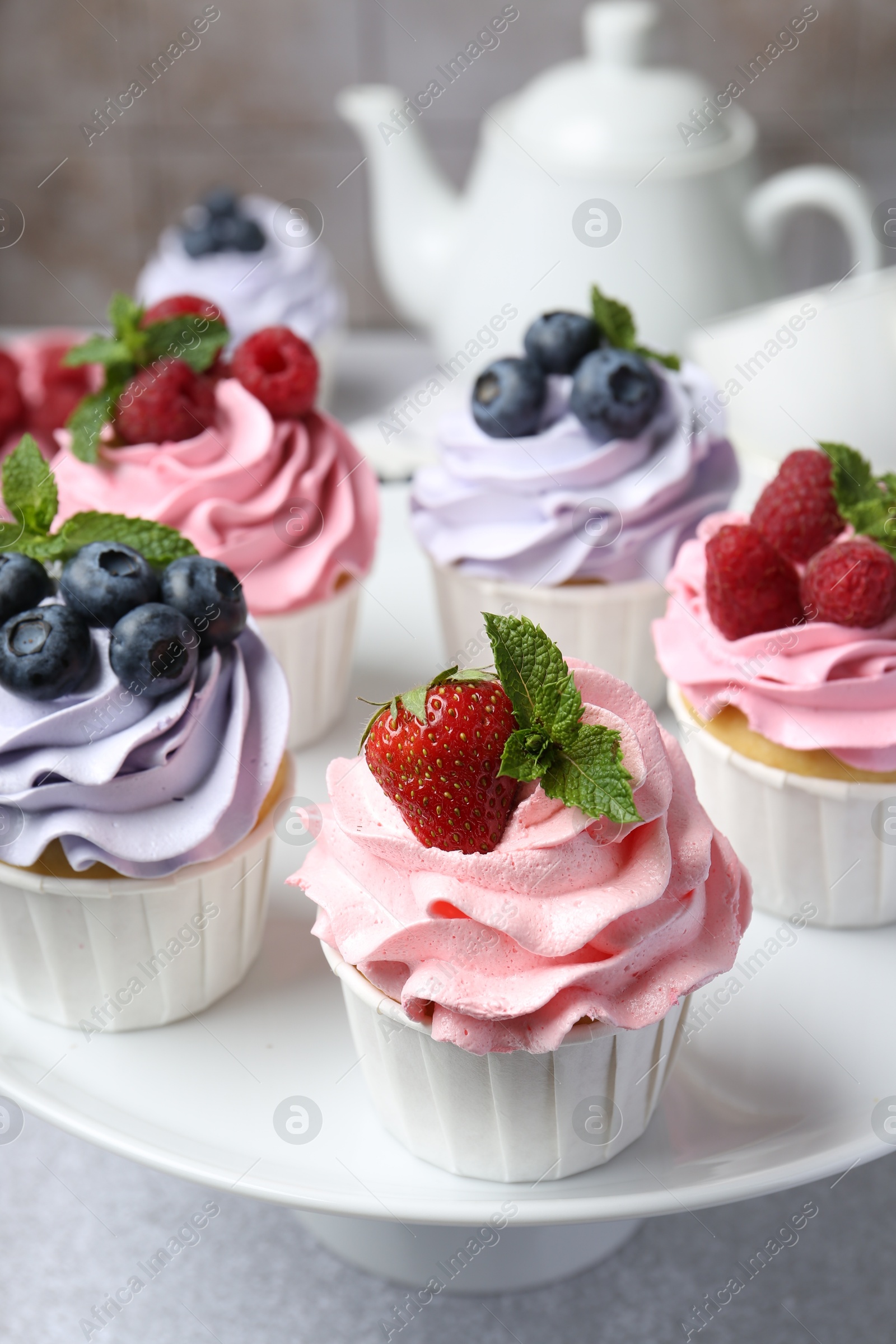 Photo of Tasty cupcakes with different berries on light grey table, closeup