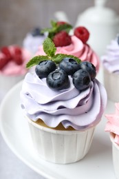 Photo of Tasty cupcakes with different berries on table, closeup