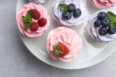 Photo of Tasty cupcakes with different berries on light grey table, top view