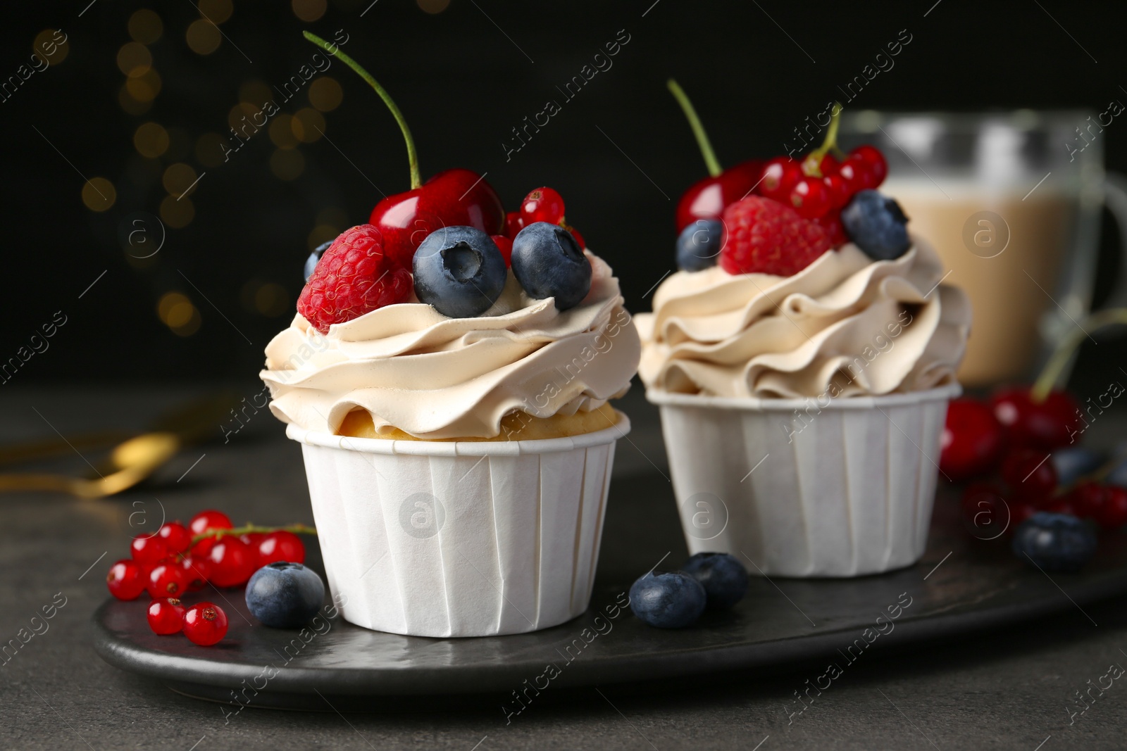 Photo of Tasty cupcakes with different berries on grey table, closeup