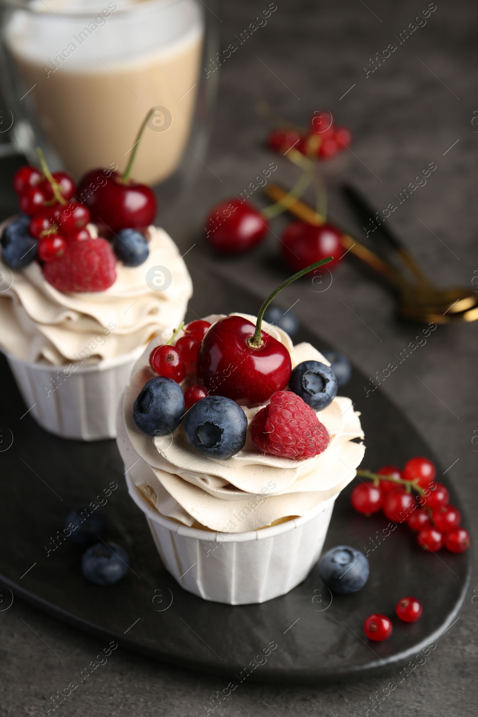 Photo of Tasty cupcakes with different berries on grey table, closeup