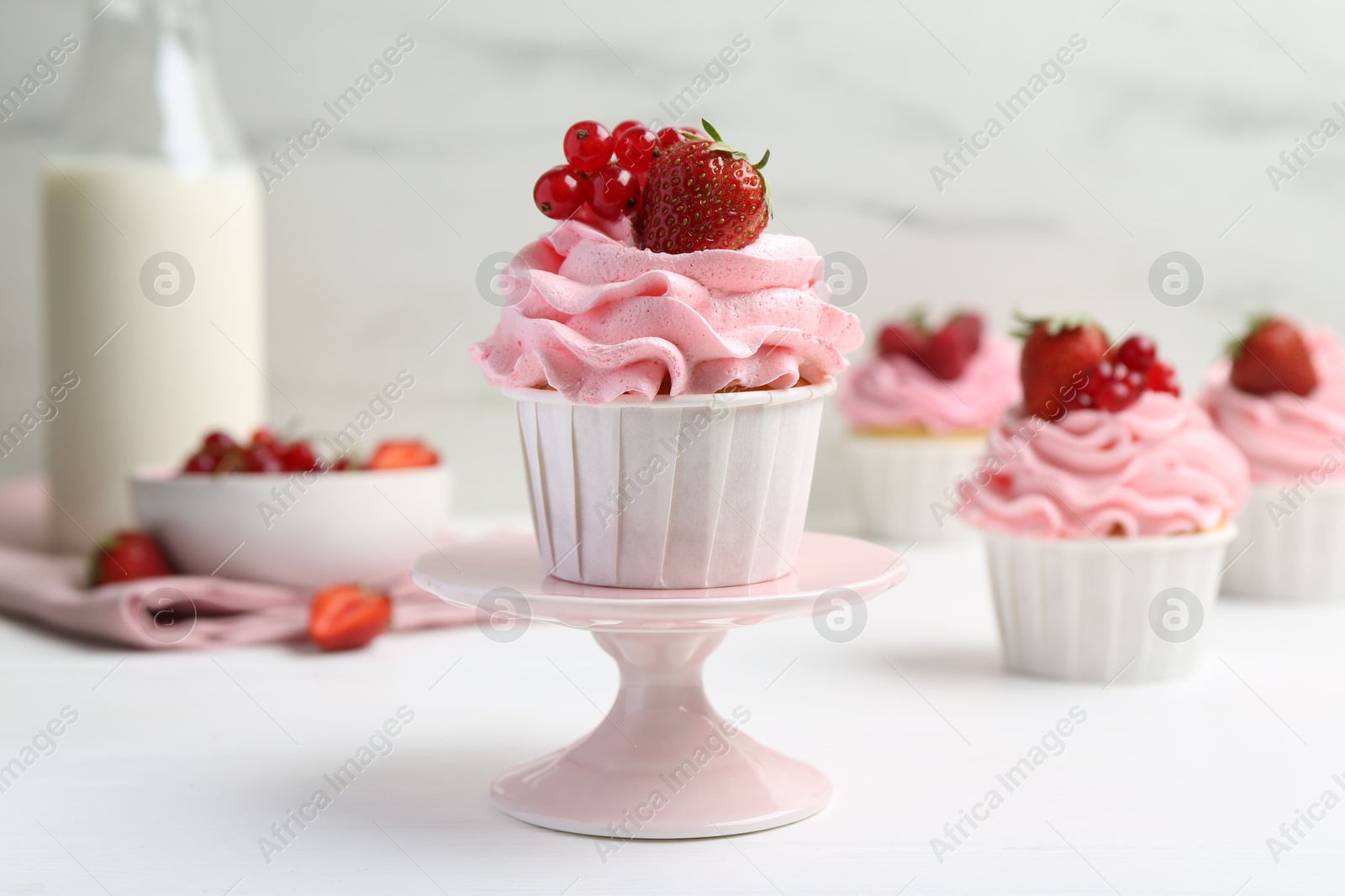 Photo of Tasty cupcakes with strawberries and red currants on white table