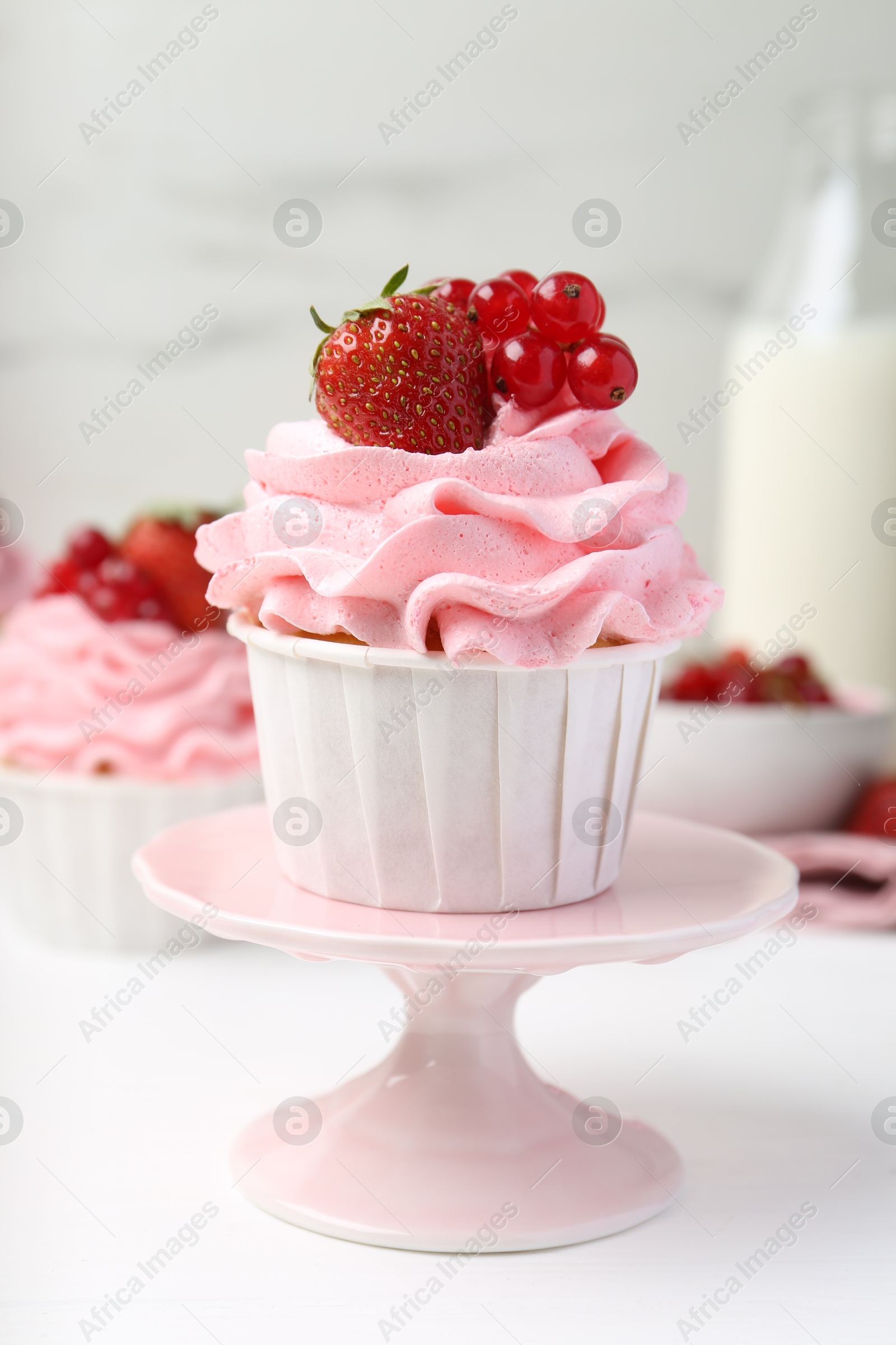 Photo of Tasty cupcakes with strawberries and red currants on white table, closeup