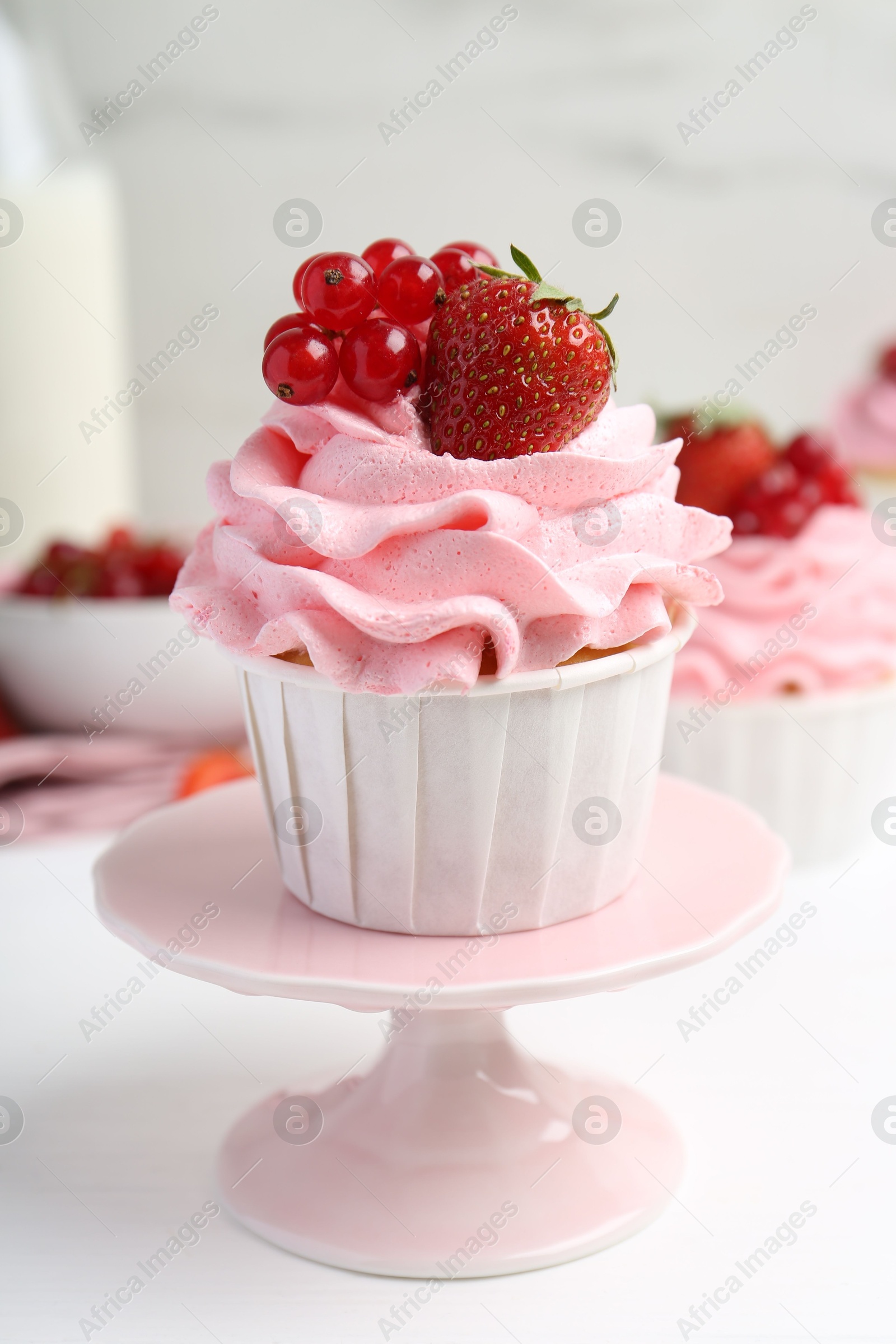 Photo of Tasty cupcakes with strawberries and red currants on white table, closeup