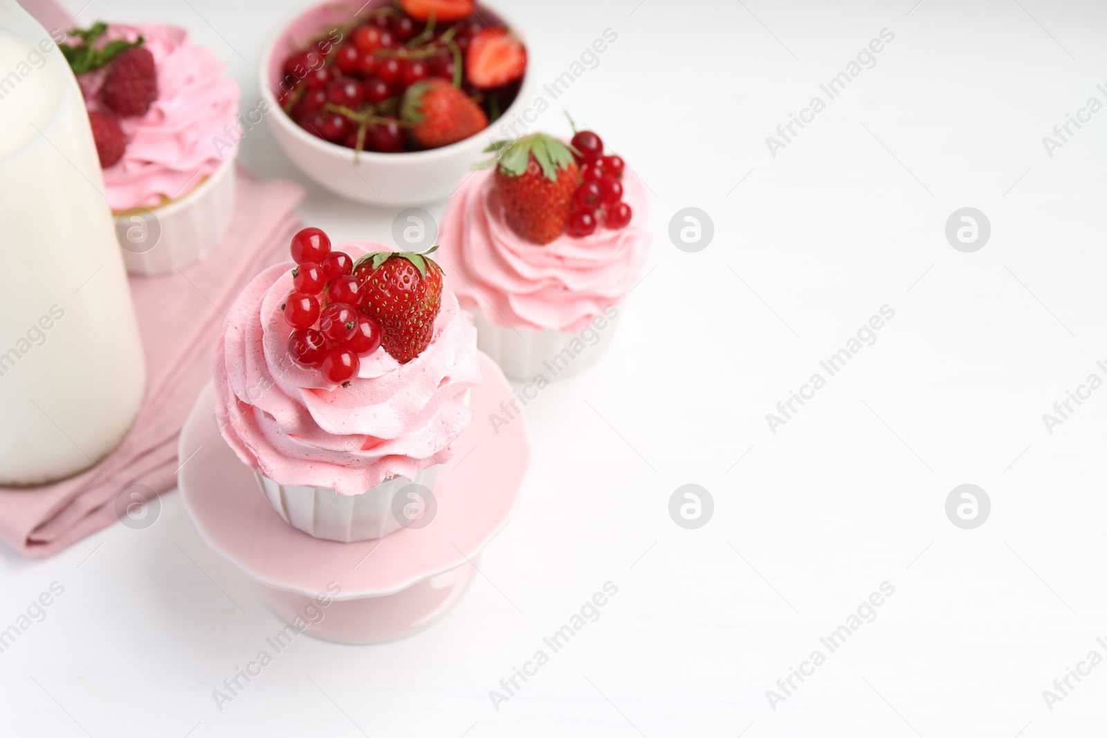 Photo of Tasty cupcakes with strawberries and red currants on white table, space for text