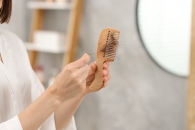 Photo of Woman taking her lost hair from comb at home, closeup. Alopecia problem