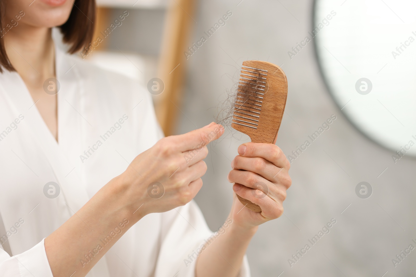 Photo of Woman taking her lost hair from comb at home, closeup. Alopecia problem