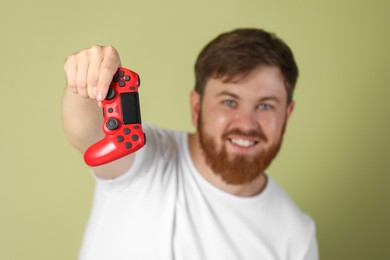 Photo of Smiling man with game controller on pale green background, selective focus