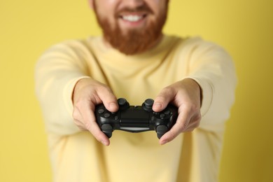 Photo of Man with game controller on pale yellow background, closeup