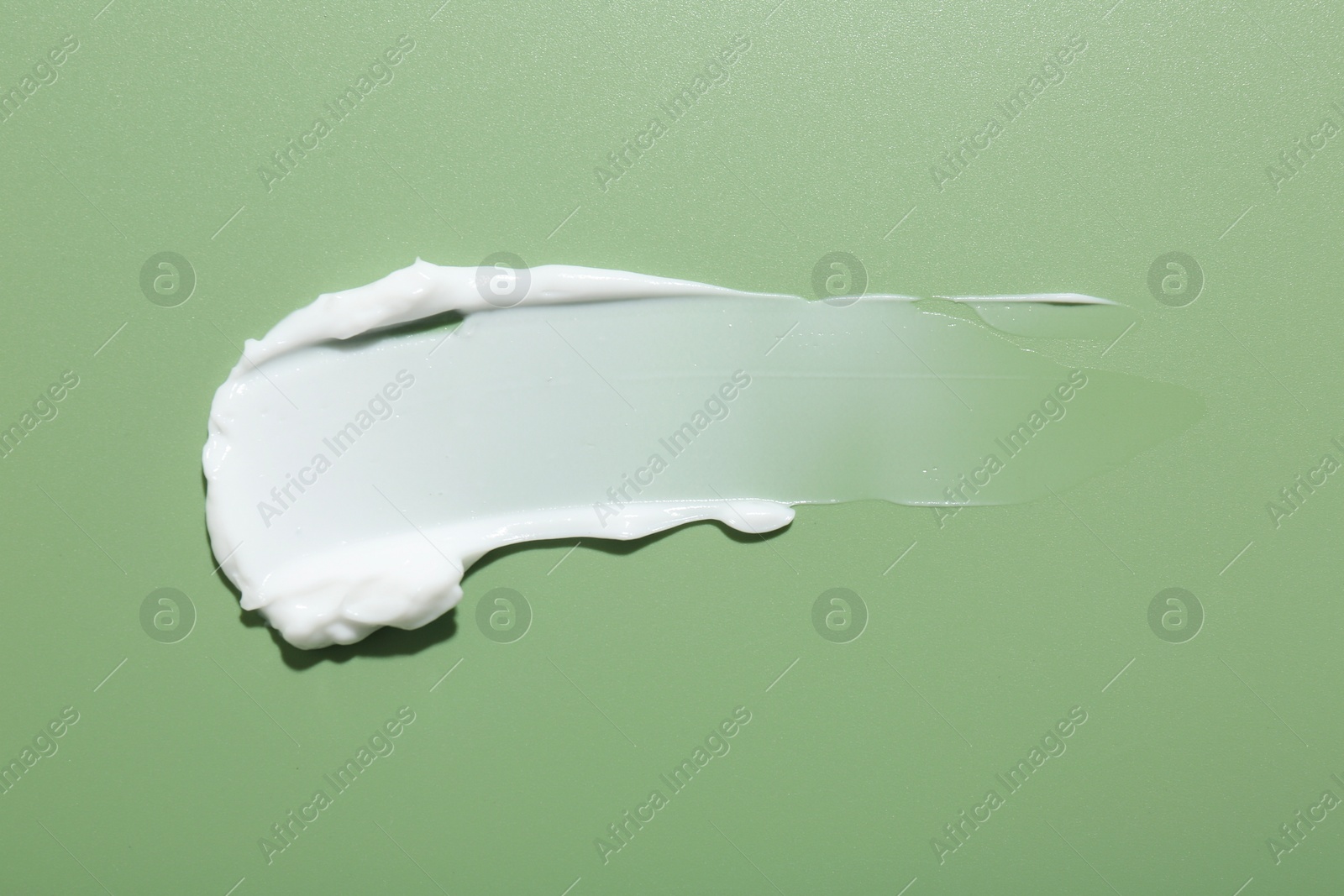 Photo of Sample of face cream on green background, top view