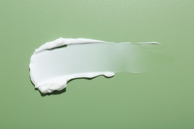 Photo of Sample of face cream on green background, top view