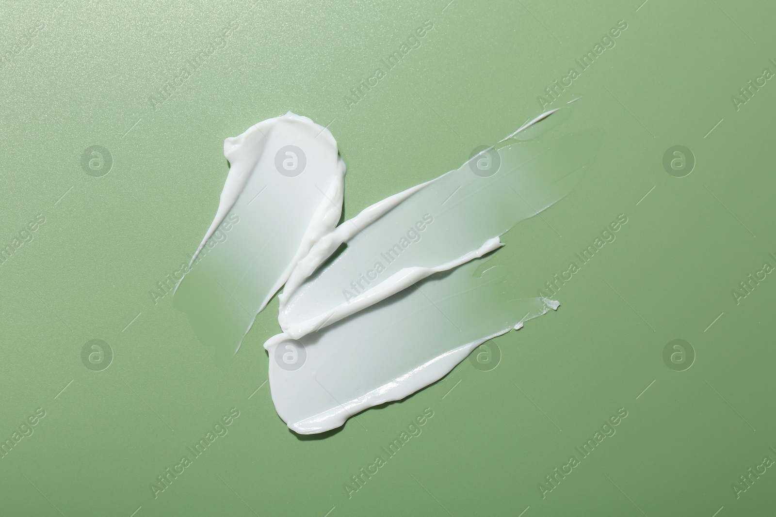 Photo of Sample of face cream on green background, top view