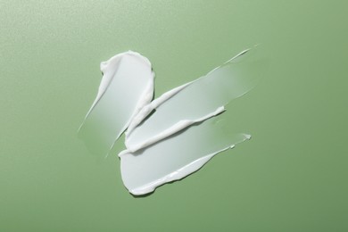 Photo of Sample of face cream on green background, top view