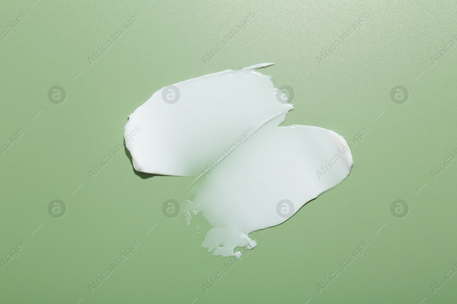 Photo of Sample of face cream on green background, top view