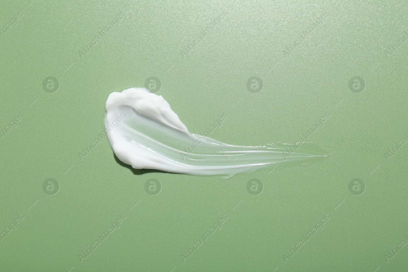 Photo of Sample of face cream on green background, top view