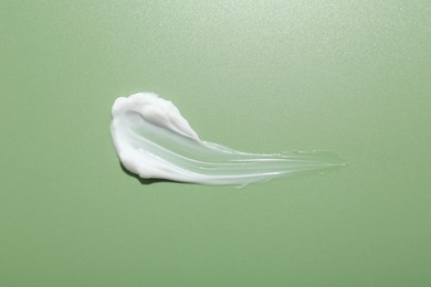 Photo of Sample of face cream on green background, top view