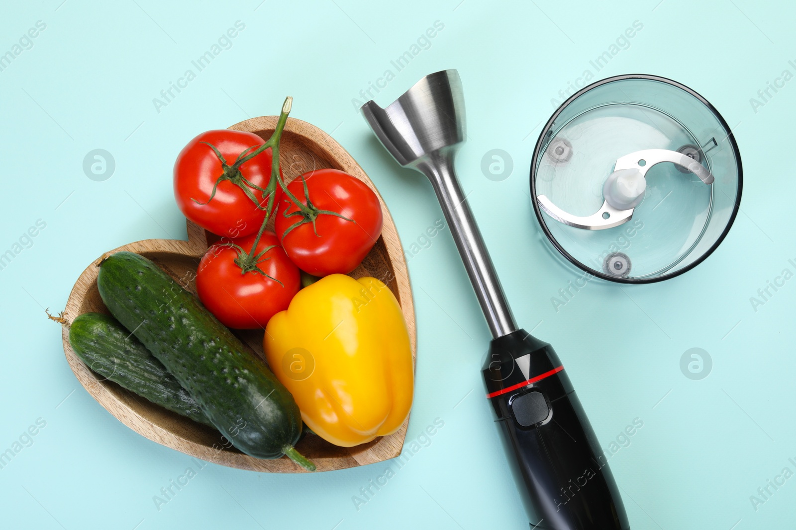 Photo of Hand blender kit and fresh vegetables on light blue background, flat lay