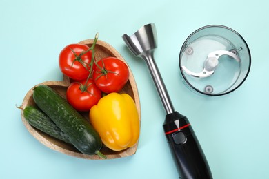 Photo of Hand blender kit and fresh vegetables on light blue background, flat lay