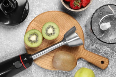 Photo of Hand blender kit and fresh fruits on grey table, top view