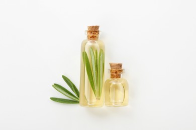 Bottles of rosemary essential oil on white background, flat lay