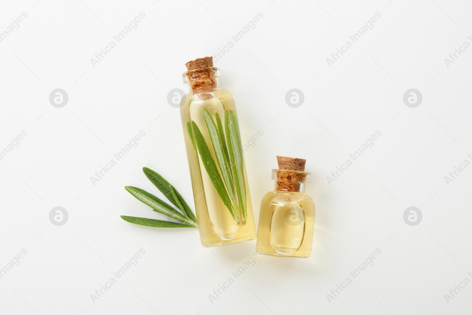 Photo of Bottles of rosemary essential oil on white background, flat lay