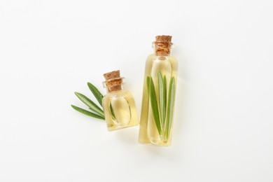 Photo of Bottles of rosemary essential oil on white background, flat lay