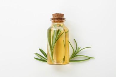 Photo of Bottle with essential oil and rosemary on white background, top view