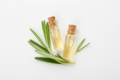 Bottles of essential oil and fresh rosemary on white background, flat lay