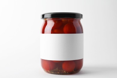 Tasty pickled tomatoes in jar on light background, closeup