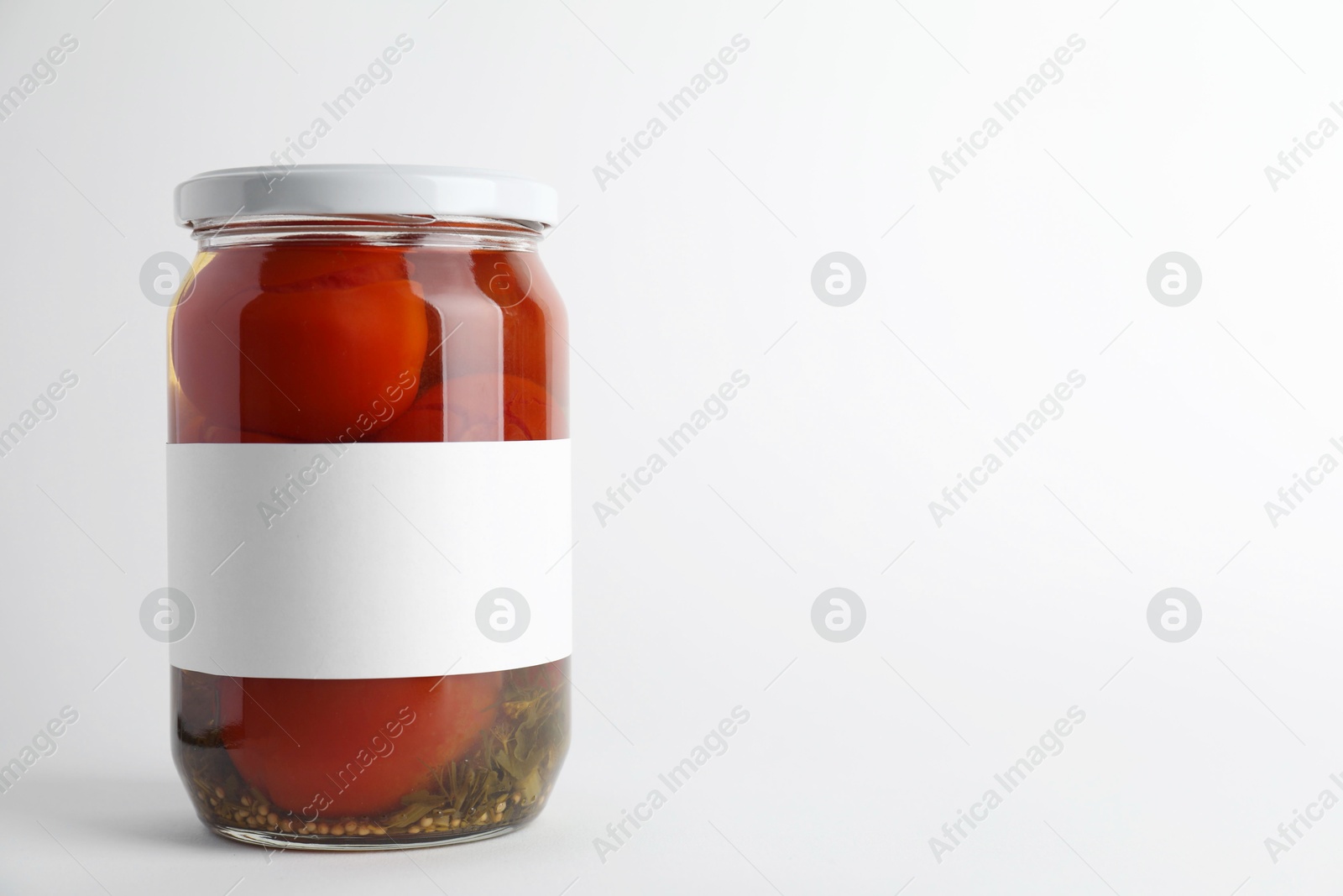 Photo of Tasty pickled tomatoes in jar on light background. Space for text