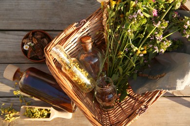 Photo of Tincture, flowers and bark chips on wooden table, top view