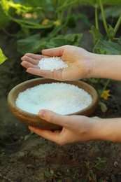 Photo of Woman holding plant fertilizer in bowl outdoors, closeup