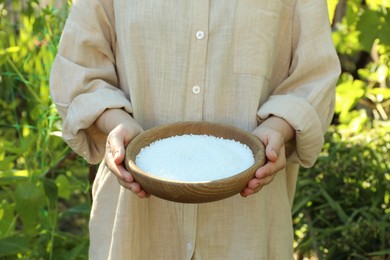 Photo of Woman holding plant fertilizer in bowl outdoors, closeup