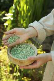 Photo of Woman holding plant fertilizer in bowl outdoors, closeup