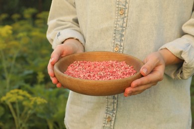 Photo of Woman holding plant fertilizer in bowl outdoors, closeup