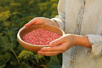 Woman holding plant fertilizer in bowl outdoors, closeup