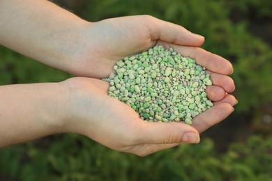 Photo of Woman holding green plant fertilizer outdoors, closeup