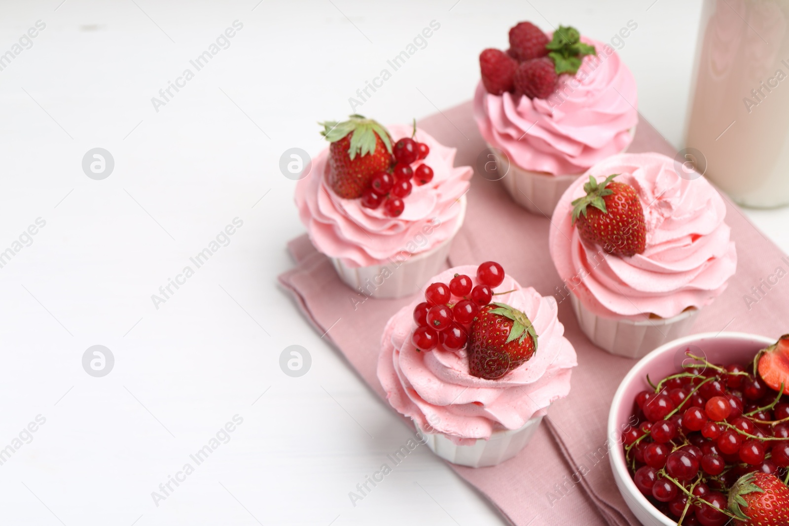 Photo of Tasty cupcakes with strawberries and red currants on white table, space for text