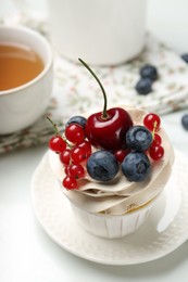 Photo of Tasty cupcake with different berries and tea on white marble table, closeup