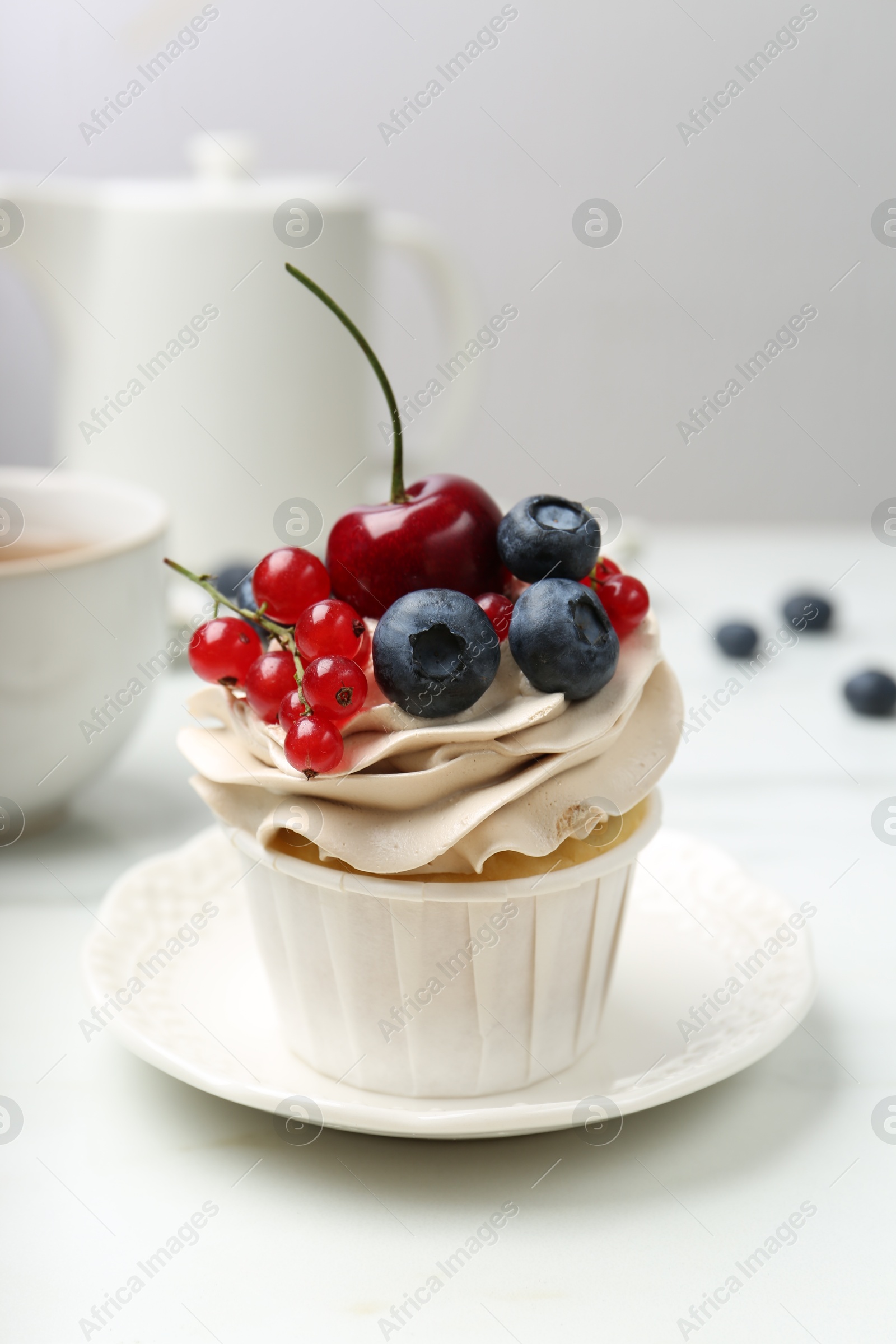 Photo of Tasty cupcake with different berries and tea on white marble table