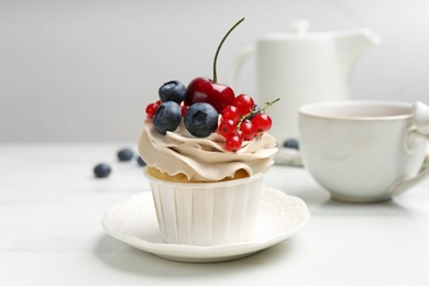 Photo of Tasty cupcake with different berries and tea on white marble table