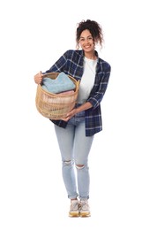 Happy woman with basket full of laundry on white background