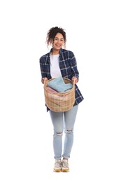 Happy woman with basket full of laundry on white background