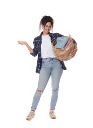 Happy woman with basket full of laundry on white background