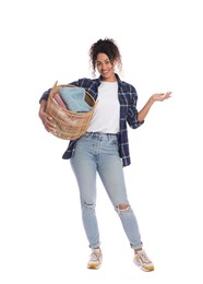 Happy woman with basket full of laundry on white background