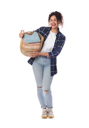 Happy woman with basket full of laundry on white background