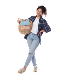 Happy woman with basket full of laundry on white background